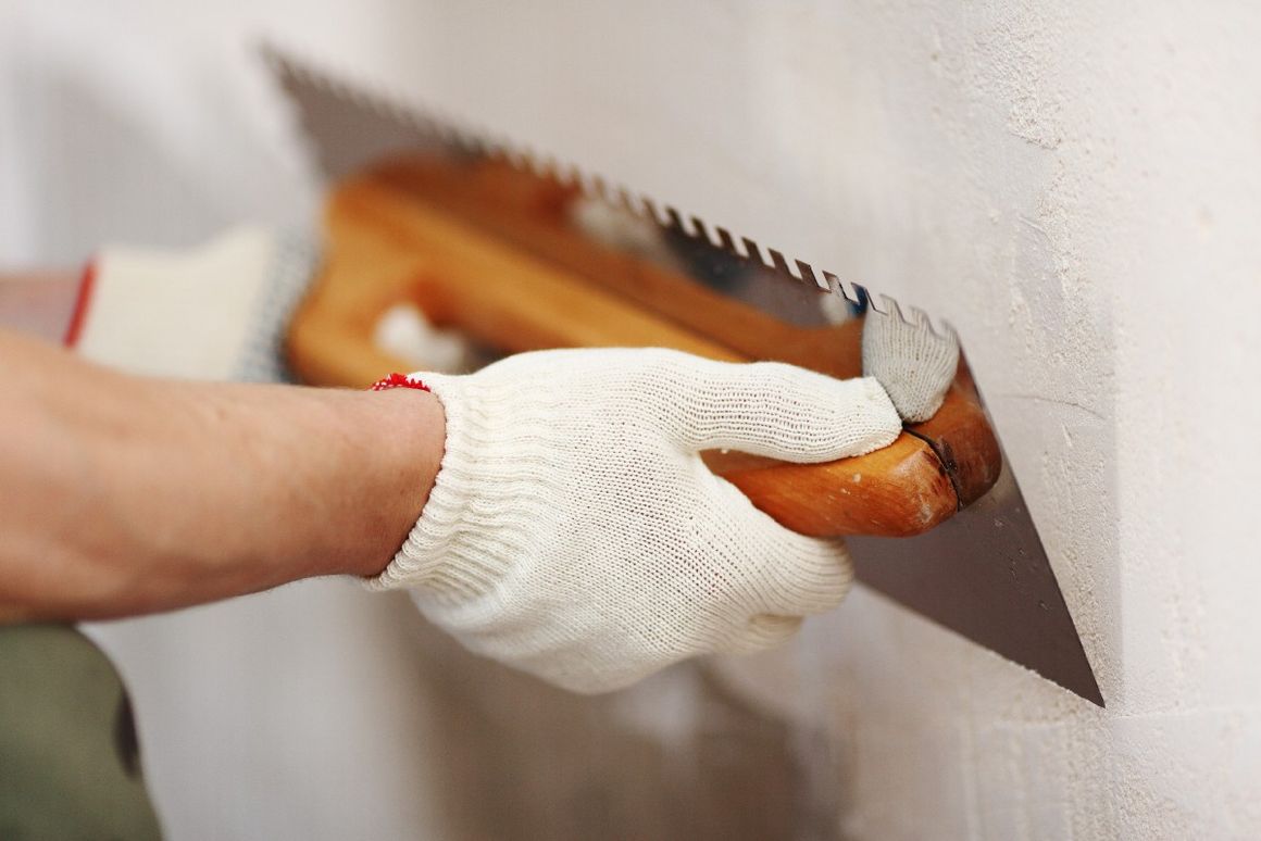 Person verputzt Wand mit Kelle